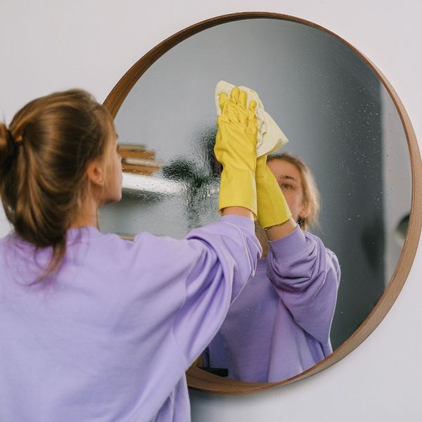 woman with gloves on cleaning mirror woman with gloves on cleaning mirror