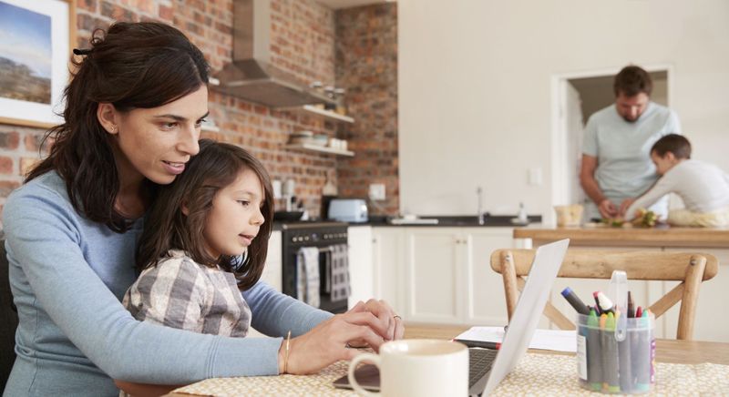 busy family working in kitchen together with the mother on the laptop