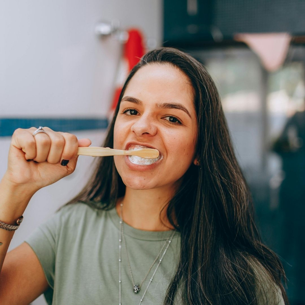 woman uses manual toothbrush on front teeth 
