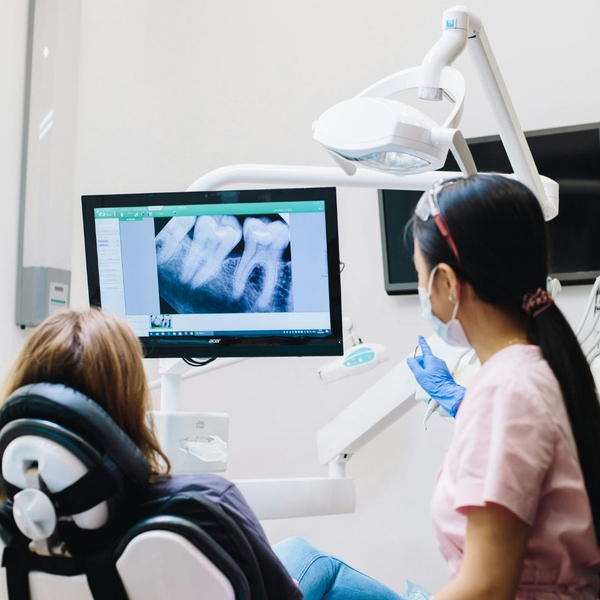 dental hygienist sitting with patient looking at dental xray
