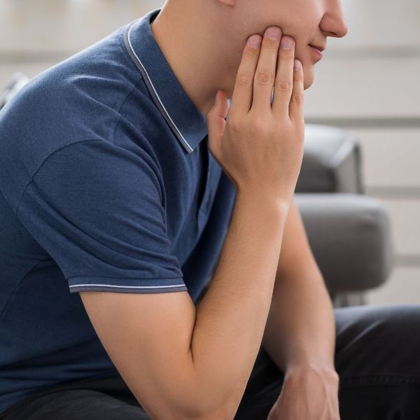 Man holding cheek, appears to have jaw pain