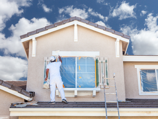 Image of a contractor painting the exterior of a home. 