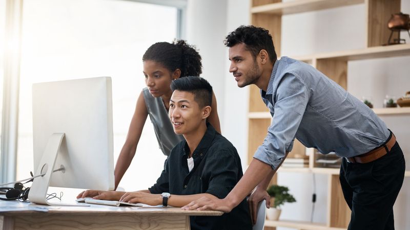 three people looking at computer screen