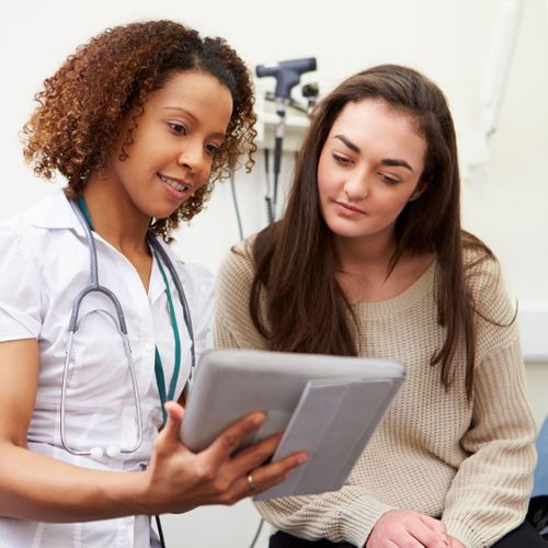 Medical professional reviewing information on a tablet with a patient