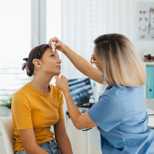 A women getting eye drops placed into her eyes