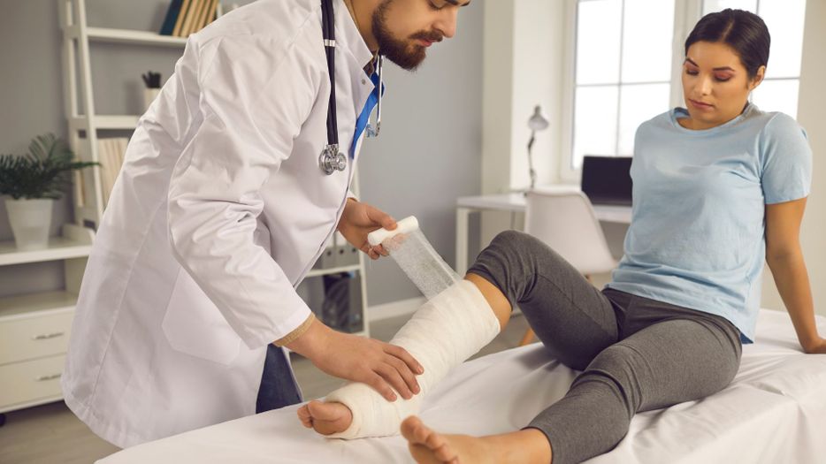 woman with fractured leg receiving care from doctor