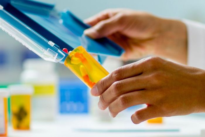 Closeup of a pharmacists pouring medication into a pill bottle