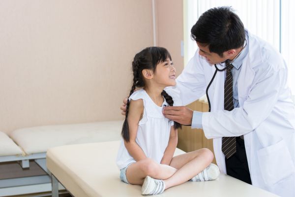 doctor giving little girl physical exam