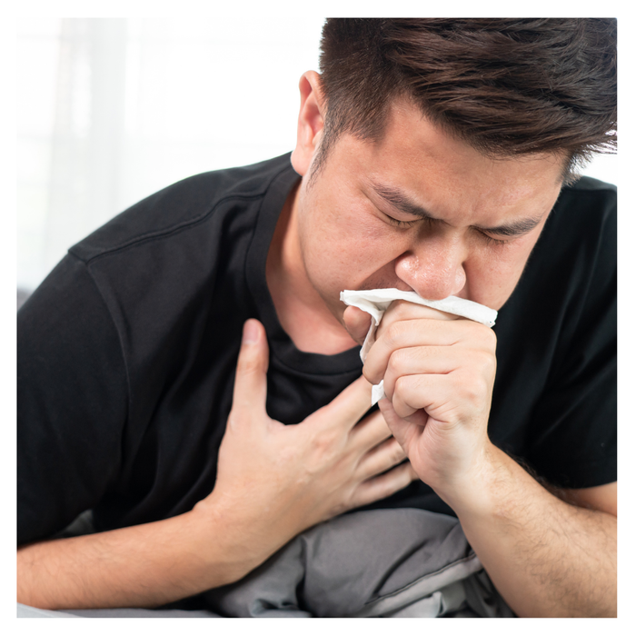 A man couhging into a tissue