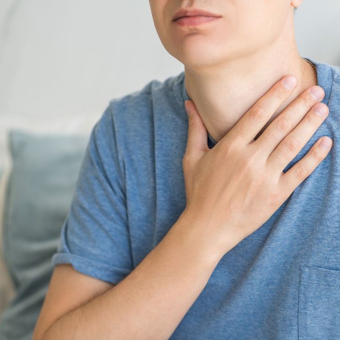 A man grabbing his throat in pain