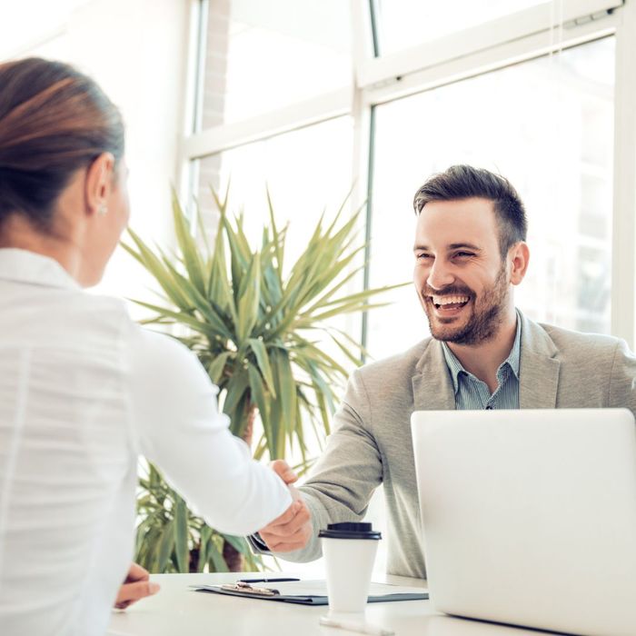 two professionals shaking hands over a desk