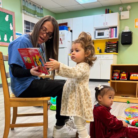 girl being read to by preschool teacher girl being read to by preschool teacher