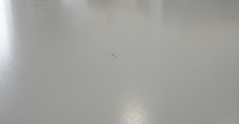 concrete floor coating with a small, subtle imperfection showing minor damage. concrete floor coating with a small, subtle imperfection showing minor damage.