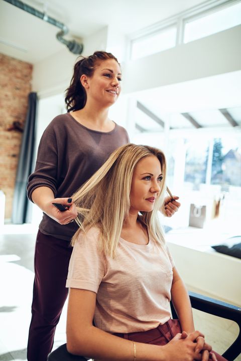 smiling-young-woman-getting-her-hair-done-at-a-sal-7YX8ZFS.jpg