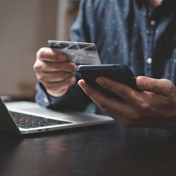 person holds credit card and smartphone at desk with laptop How Lee H Moultrie & Associates LLC Simplifies Your Life Insurance Choices 3.jpg