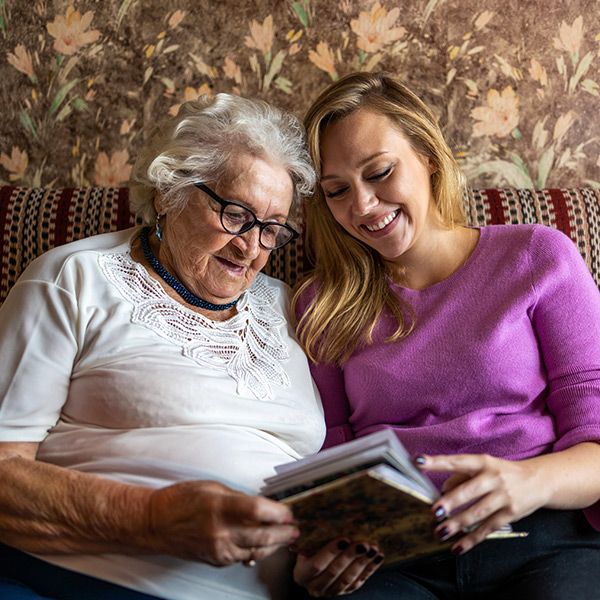 young woman reading to elderly woman