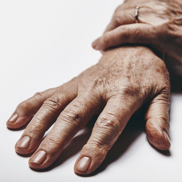A pair of old woman hands on a grey surface.