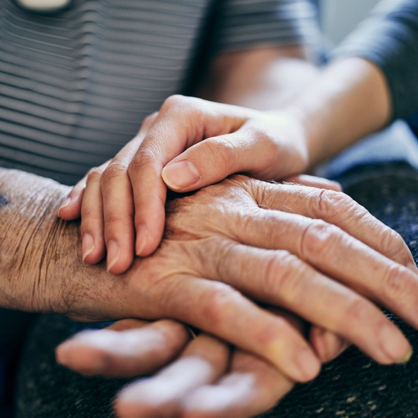 senior care worker holding patients hands