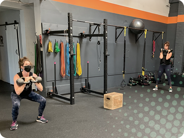 photo of women doing squats with kettlebells