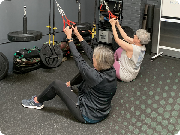 photo of 2 women working on TRX ropes