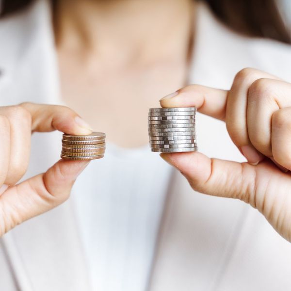 Woman holding two stacks of coins, on smaller and bigger