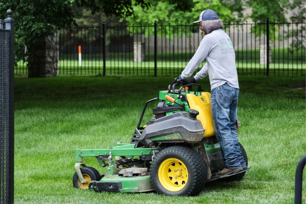 Rooted landscaper riding a lawnmower