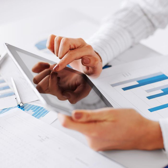 woman using a tablet on a table with graphs and charts on it