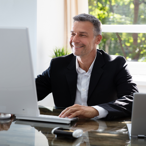 guy in a suit smiling at a computer screen