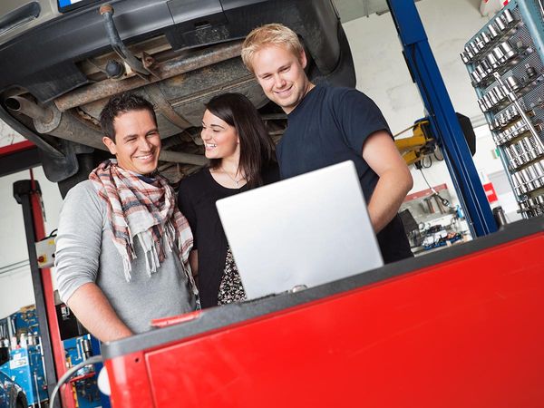 Auto technician smiling and talking to a smiling couple