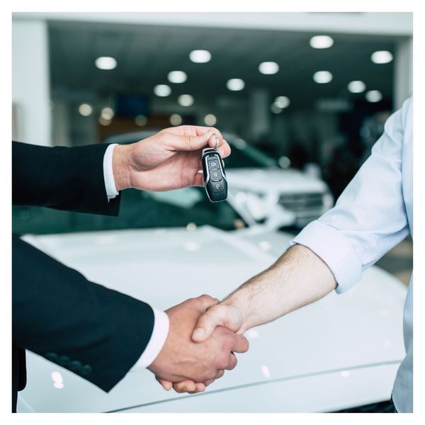 close up of handshake and car salesman handing over car keys