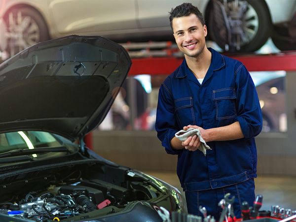 Mechanic smiling in front of car