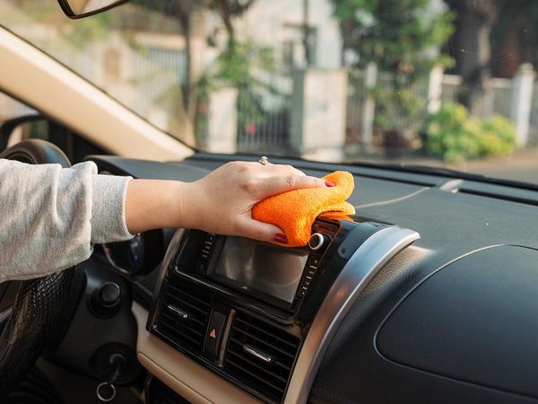 Woman cleaning dash of car with a rag