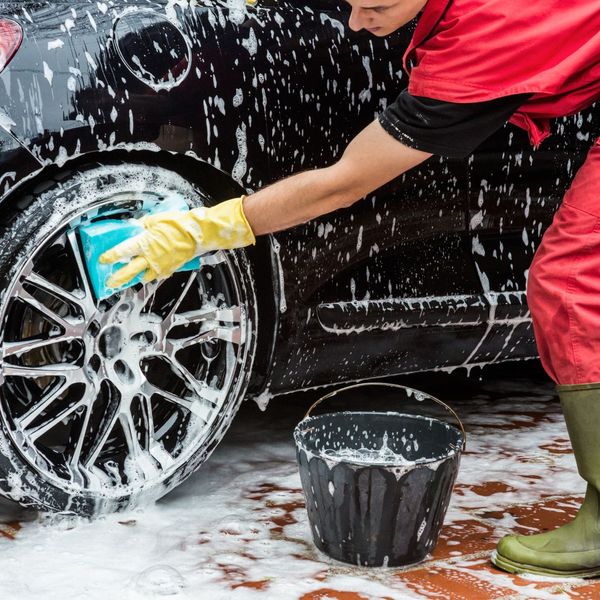 someone washing a car with a sponge and bucket