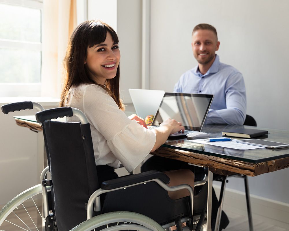 photo of man and woman in a wheelchair working in an office