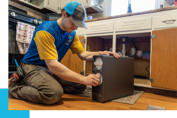 Plumber working on water filtration system under sink