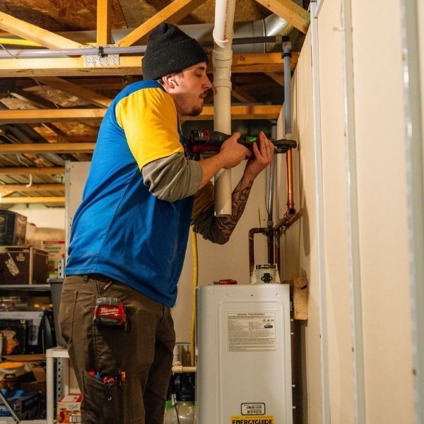 Licensed plumber installing a new tankless water heater for a home.