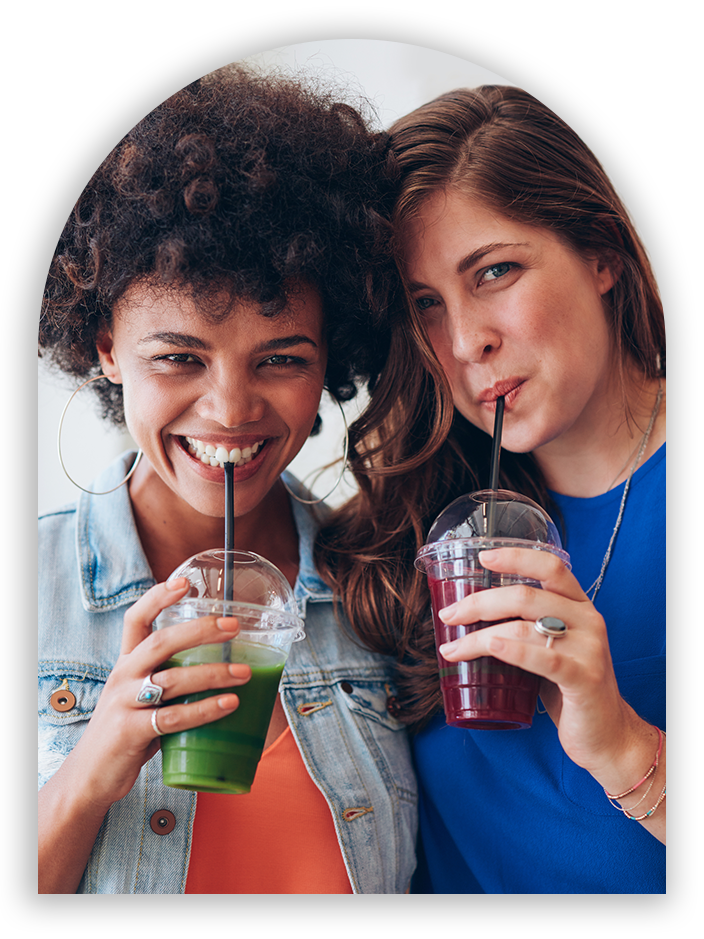 Two women drinking smoothies together