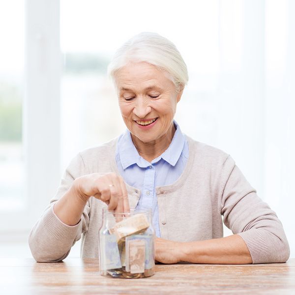 Image of an older woman smiling and placing money in a glass jar.