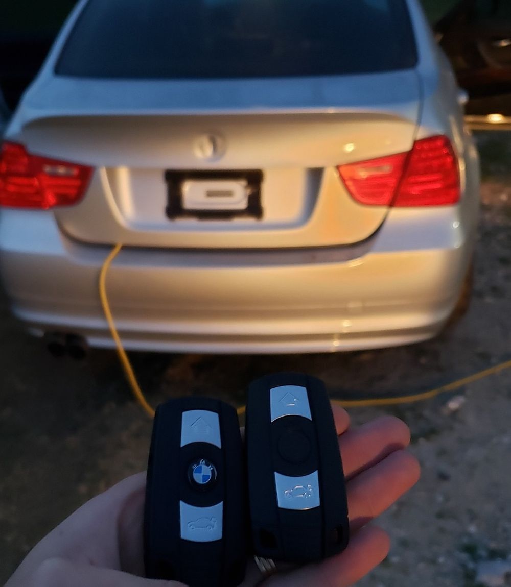 Back of a silver BMW with someone holding up two key fobs