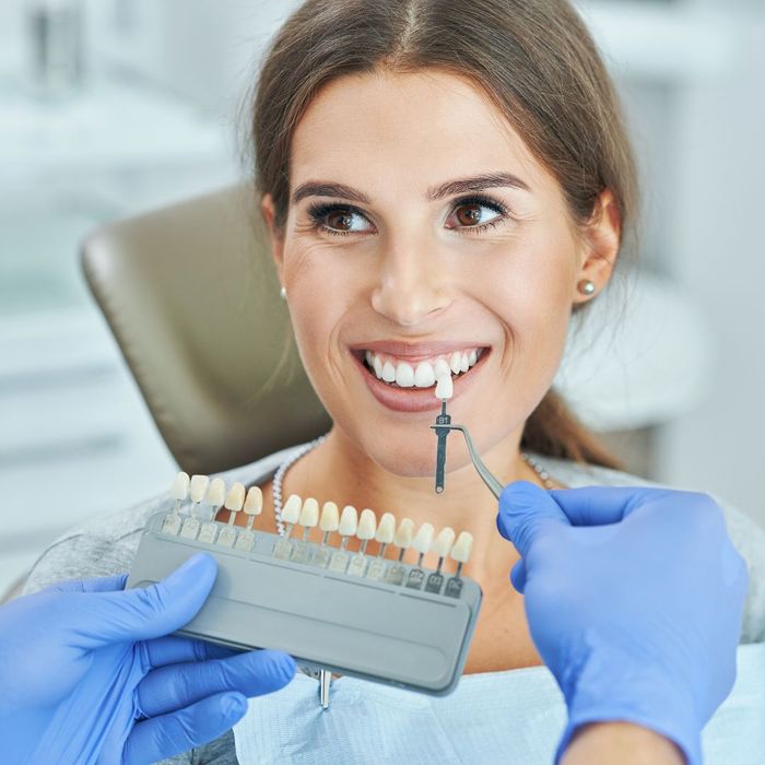 Woman choosing color of teeth at dentist