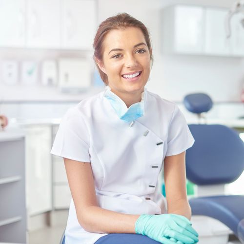 A happy dental hygienist sitting in a dental office