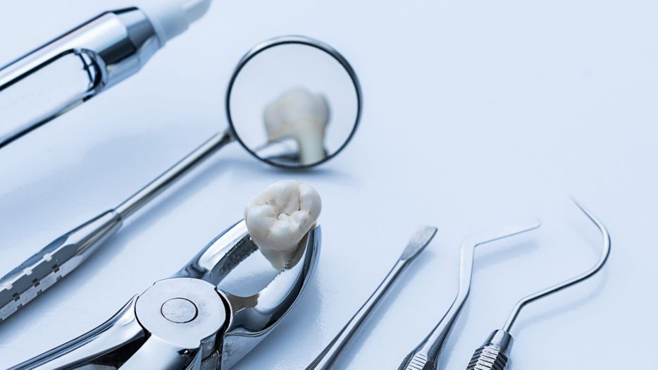 Various dental tools, with one grasping a tooth.