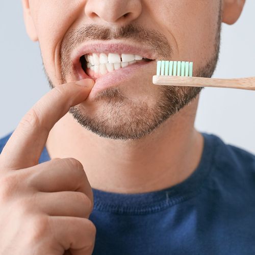 A man holding down his lip while holding a toothbrush close to his mouth