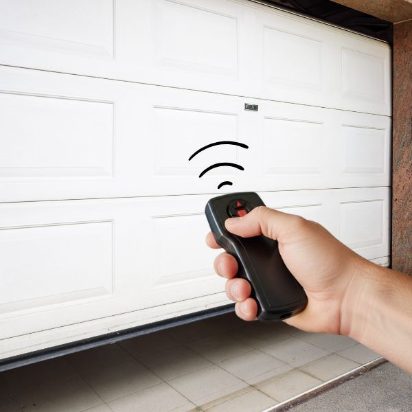 hand holding a garage door remote, pointing at a non-responsive garage door