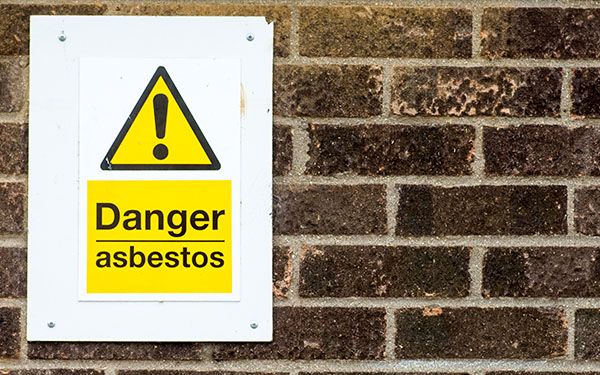 A brick wall with a sign that says "Danger asbestos"