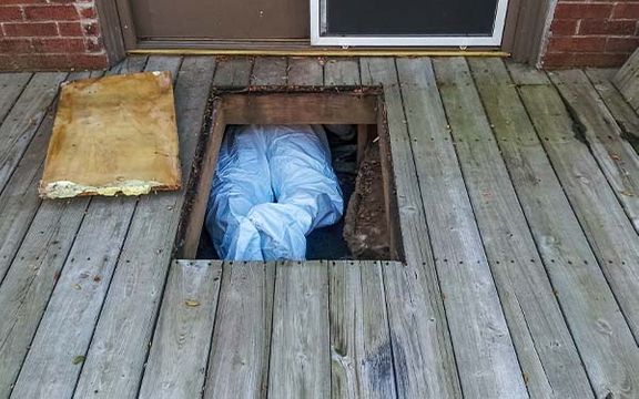 Asbestos removal specialist working in a crawlspace