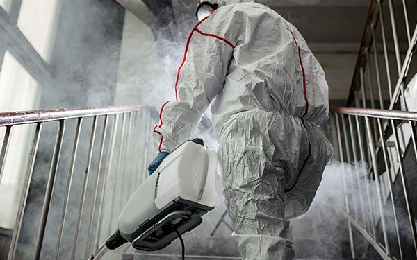 an image of a man in hazmat suiting spraying mold
