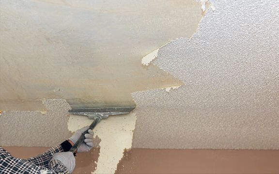 An image of someone scraping off popcorn ceiling