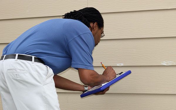 Home inspector inspecting siding