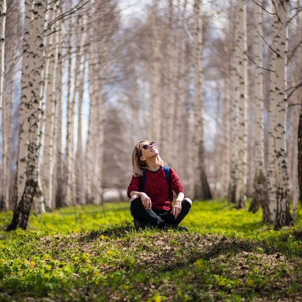 a woman sitting in the middle of a forest